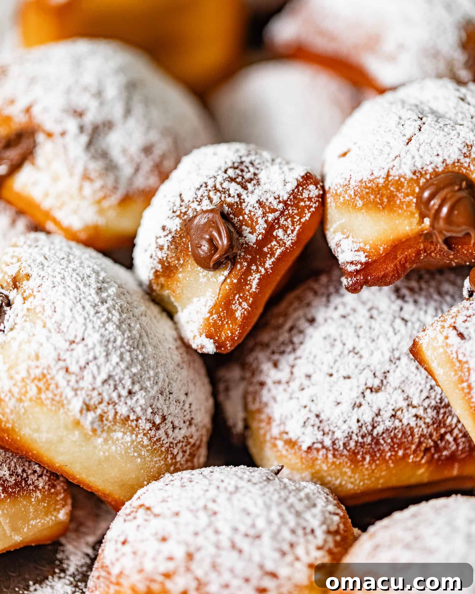 Nutella beignets covered in powdered sugar on a serving tray