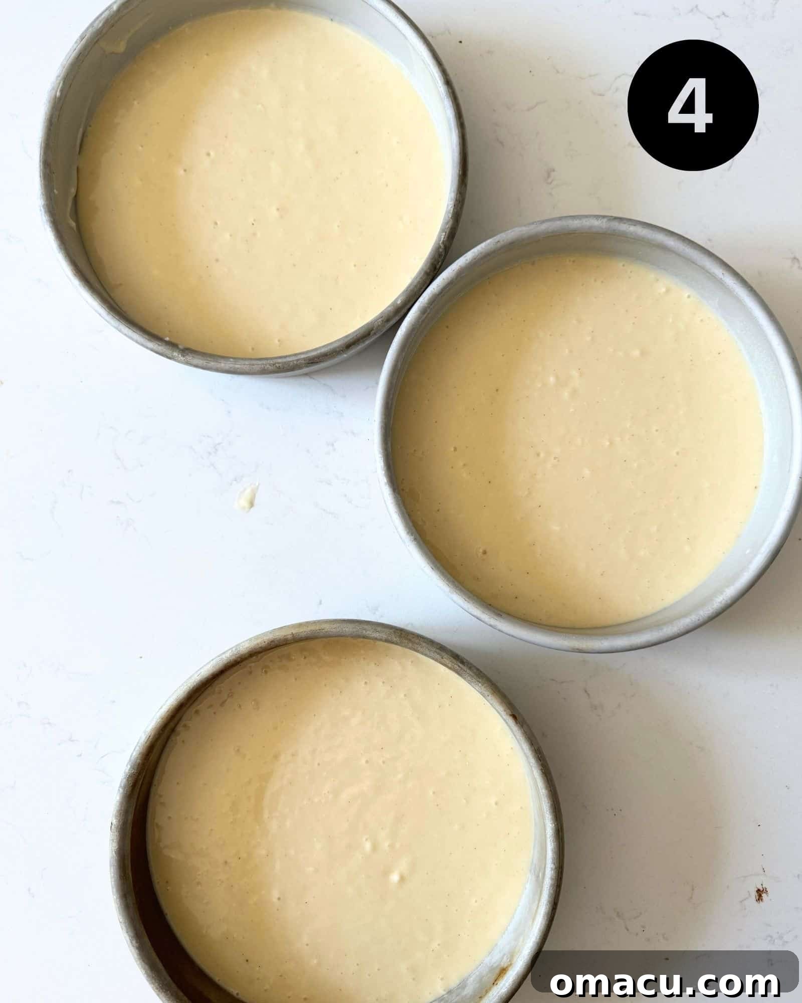 Cake batter divided equally among three 8-inch cake pans, ready for baking.