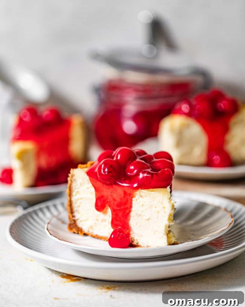 Multiple slices of cherry cheesecake, each on a white plate, adorned with a generous dollop of glossy cherry sauce.