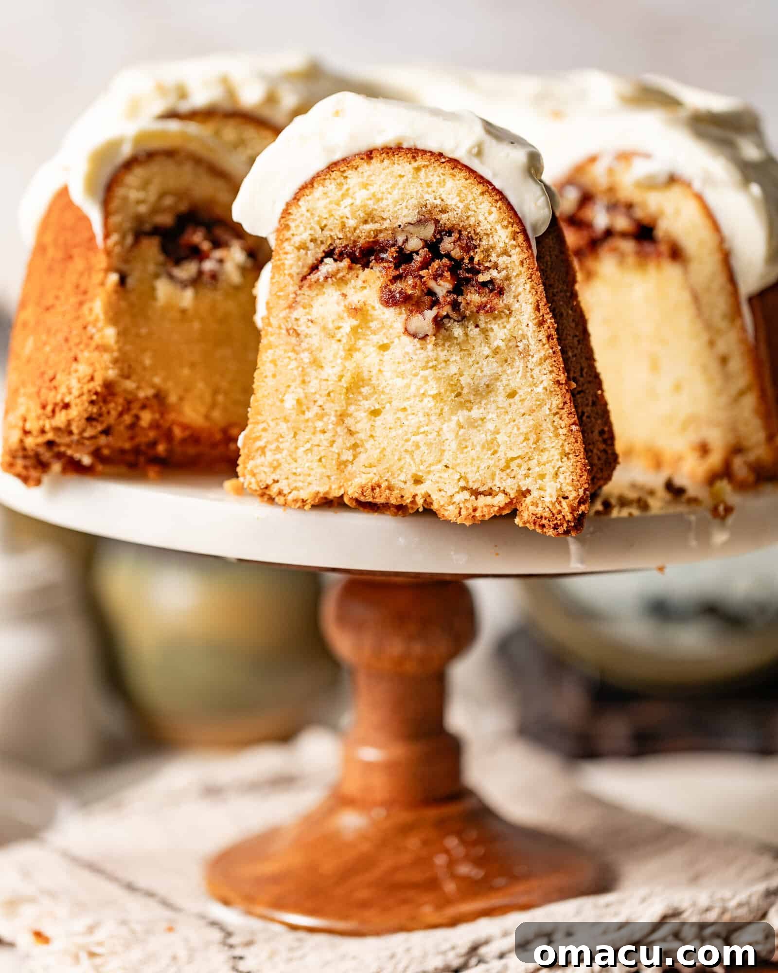 A beautifully sliced Sock it to Me Cake on a cake stand, revealing its inviting inner pecan streusel layer and golden-brown crust.