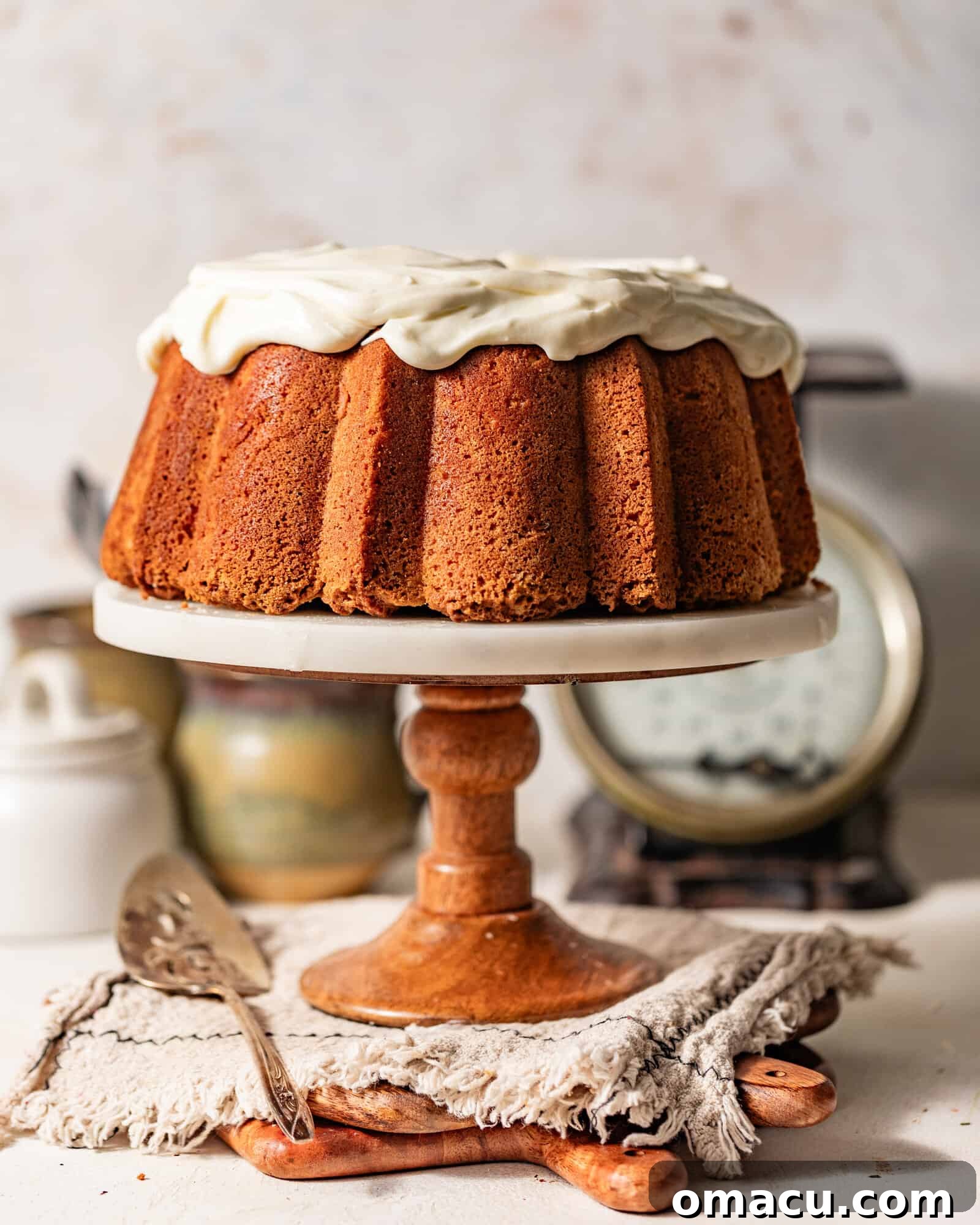 A stunning Sock it to Me Cake elegantly presented on a cake stand, generously topped with a rich and smooth cream cheese frosting.