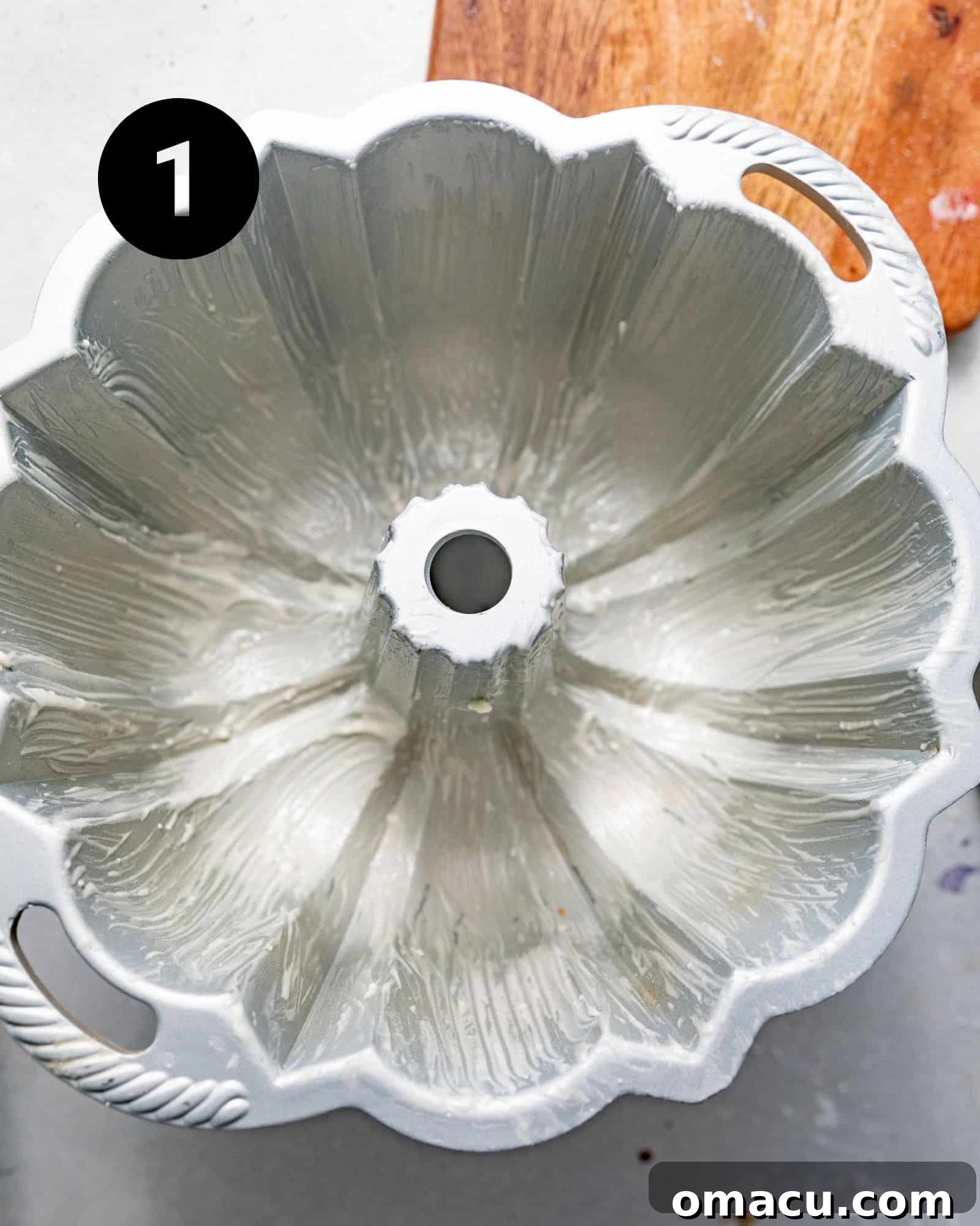 A bundt pan meticulously greased with nonstick baking spray, ready for baking.