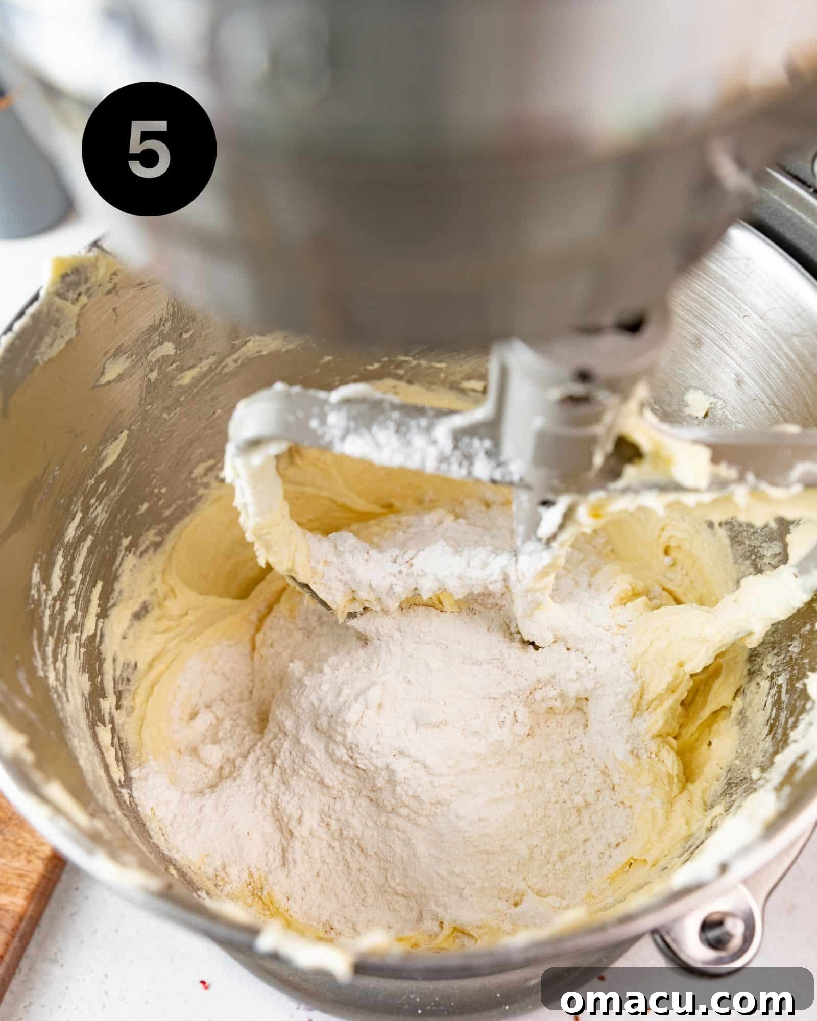 Cake batter in a stand mixer with half of the dry ingredients freshly incorporated.