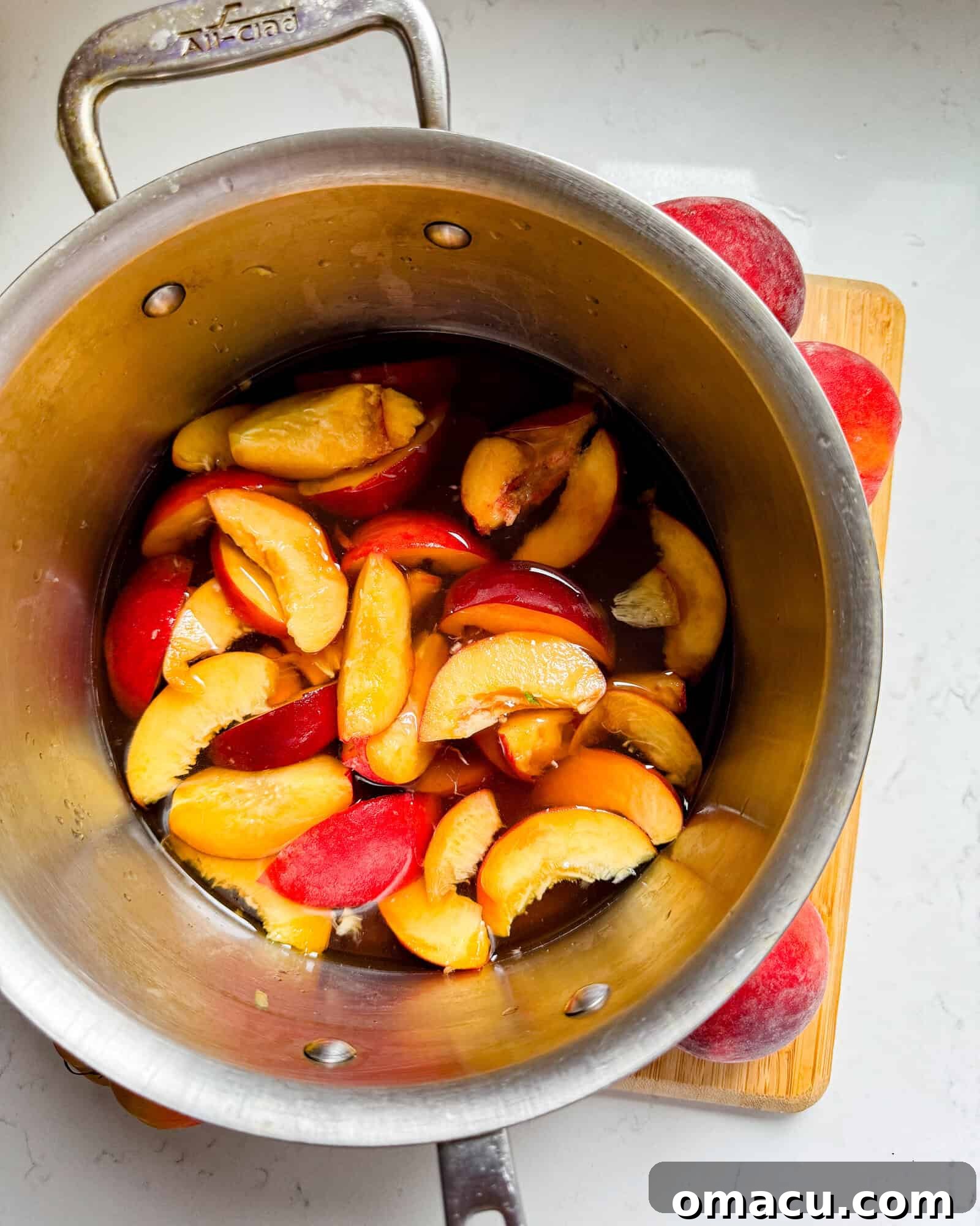 A saucepan filled with sliced peaches, brown sugar, and water, ready to be simmered into a delicious syrup.