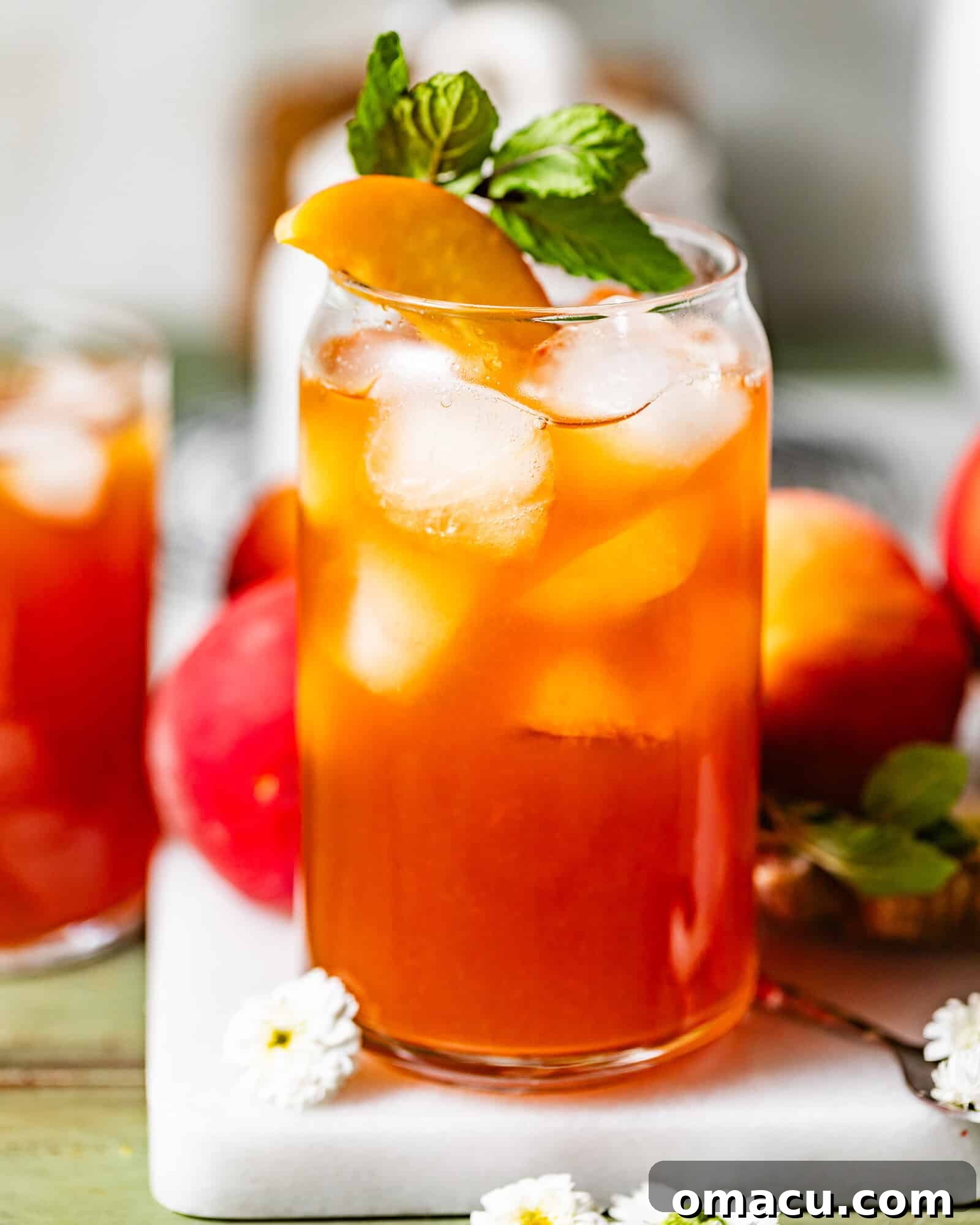A refreshing glass of homemade peach tea, beautifully garnished with bright lemon slices and fresh mint sprigs, perfectly chilled and ready to be savored.