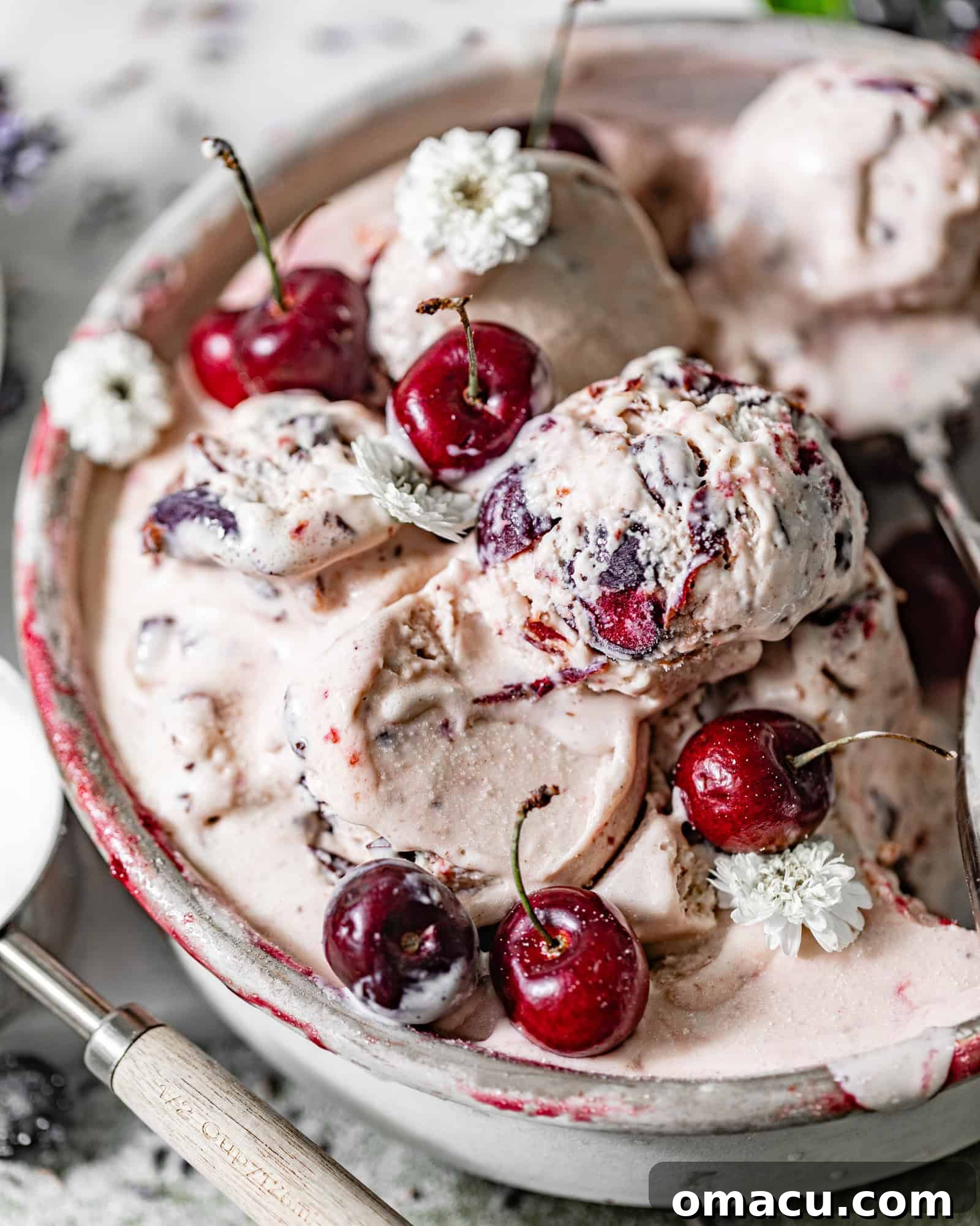 Black cherry ice cream scooped into a metal round pan with fresh cherries.
