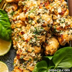 Garlic parmesan chicken skewers on a serving plate with fresh basil and lemon slices, a perfect appetizer or main course.