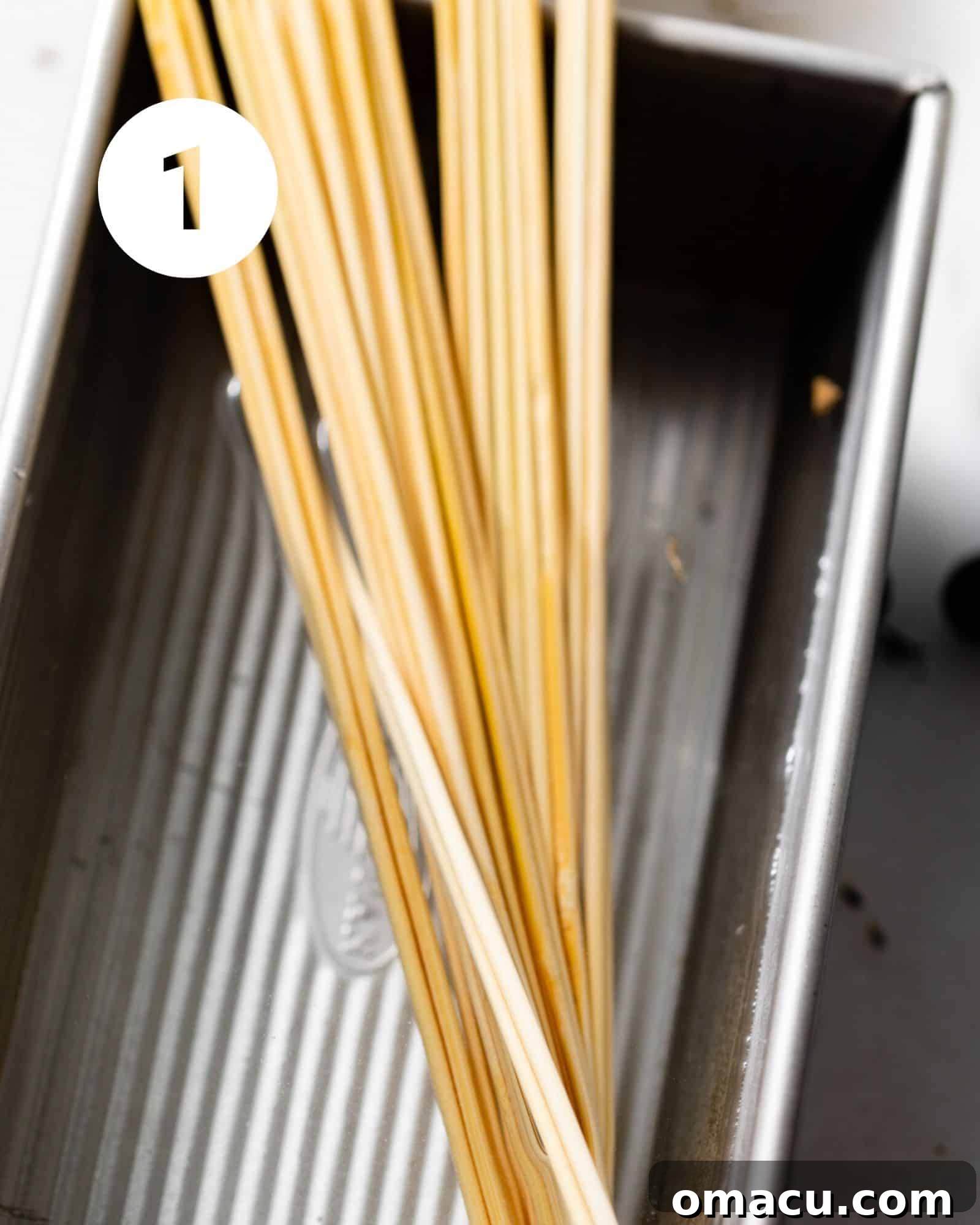 Wooden skewers soaking in a bowl of water, a crucial step before cooking to prevent burning.