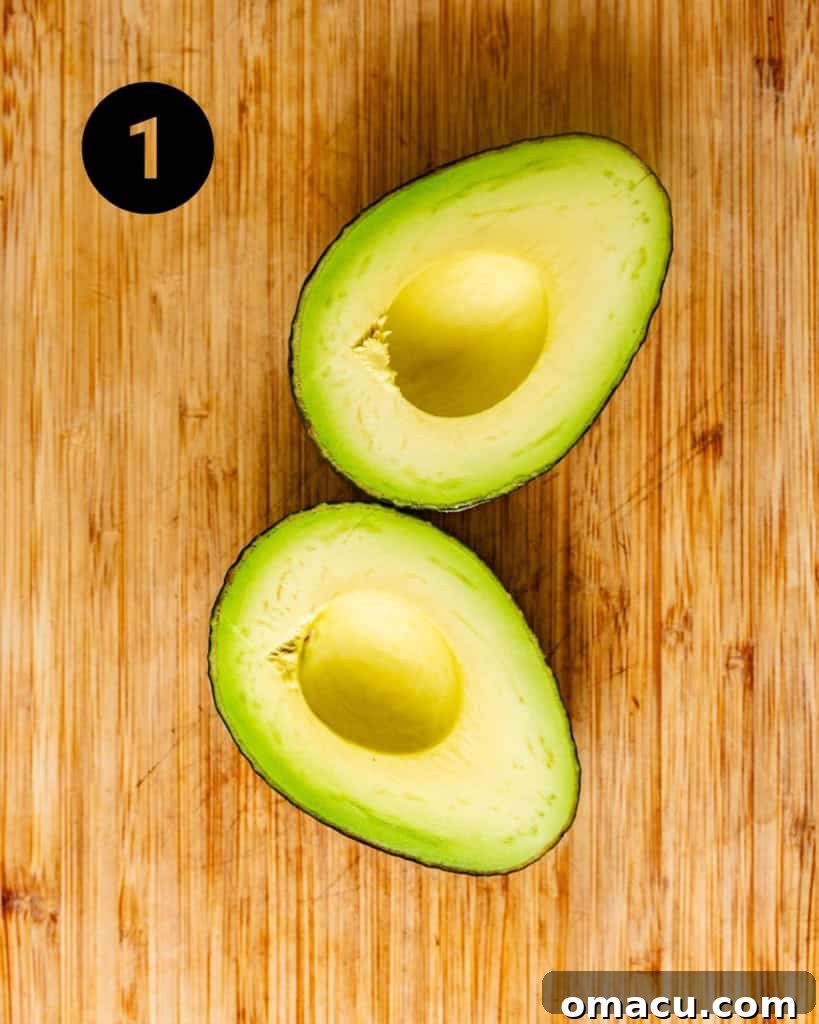Ripe avocados on a cutting board, neatly cut in half with the pits removed, showing their vibrant green flesh.