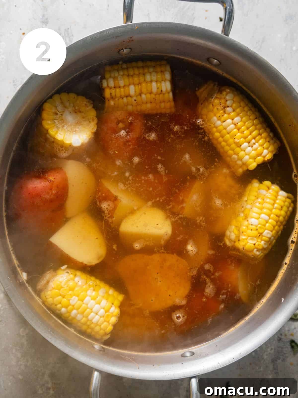 Corn and red potatoes boiling in a large pot of seasoned water.