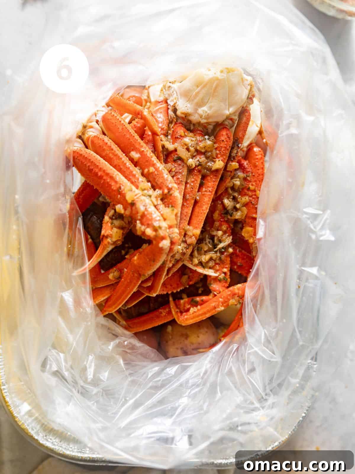 A sealed seafood boil bag filled with ingredients, resting in an aluminum pan before baking.