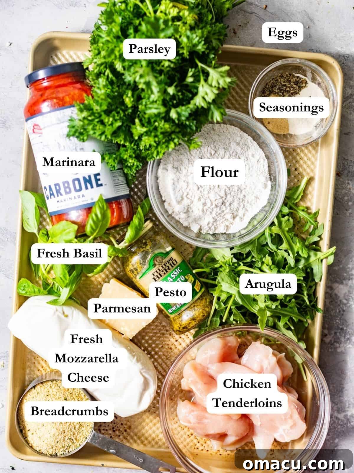 A visually appealing flat lay of all necessary ingredients for the chicken parmesan sandwich: chicken tenderloins, fresh parsley and basil, grated parmesan, fresh mozzarella, pesto, marinara sauce, thick Texas toast, various seasonings, eggs, flour, and crunchy panko breadcrumbs.