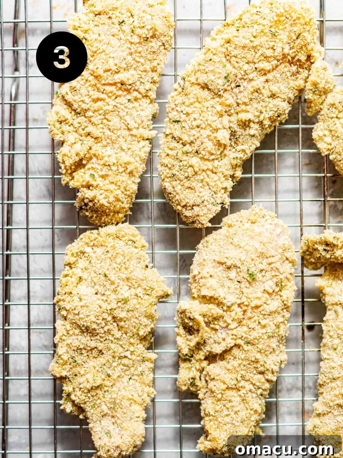 Several chicken cutlets perfectly coated in breading, resting on a metal wire rack, ready for frying.