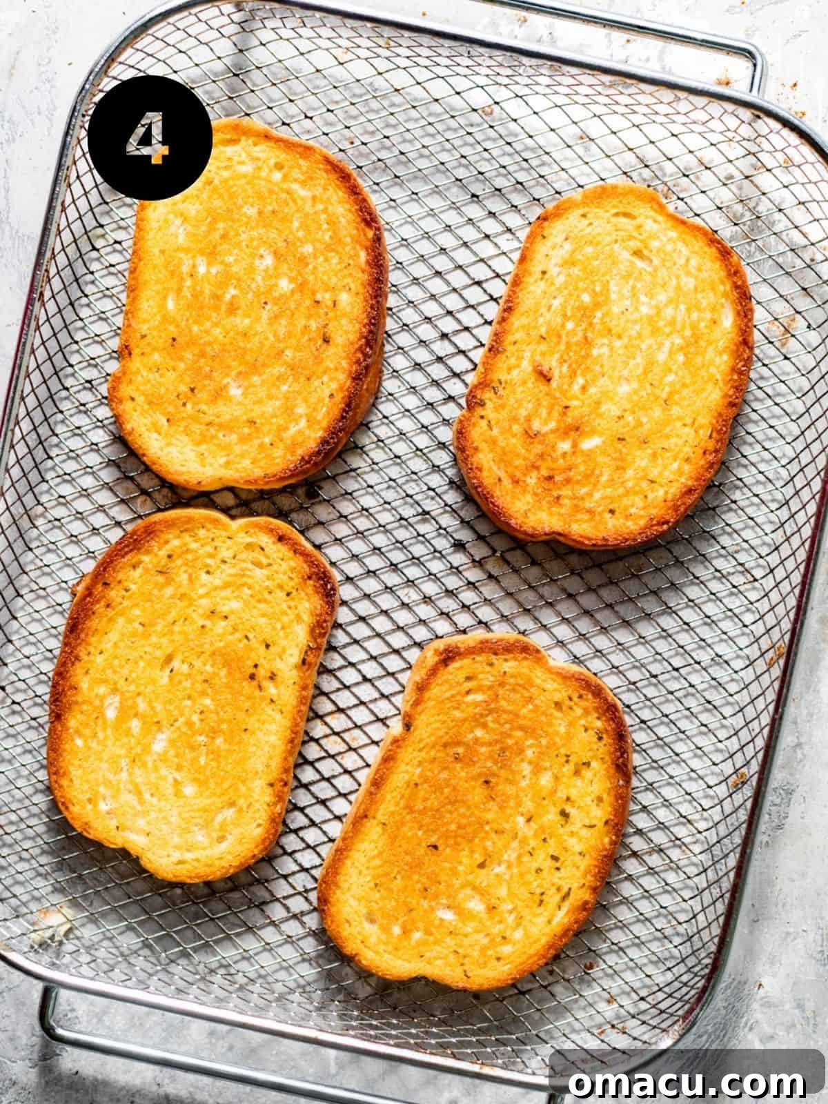 Two slices of golden-brown toasted Texas toast cooling on a wire rack, waiting for assembly.