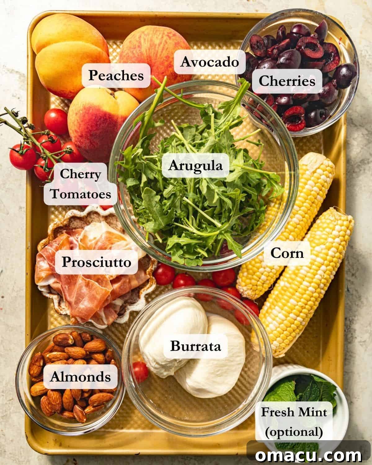 A colorful array of fresh ingredients for a burrata arugula salad, including bright green arugula, golden corn, juicy peaches, ruby red cherries, cherry tomatoes, creamy avocado, and delicate mint.