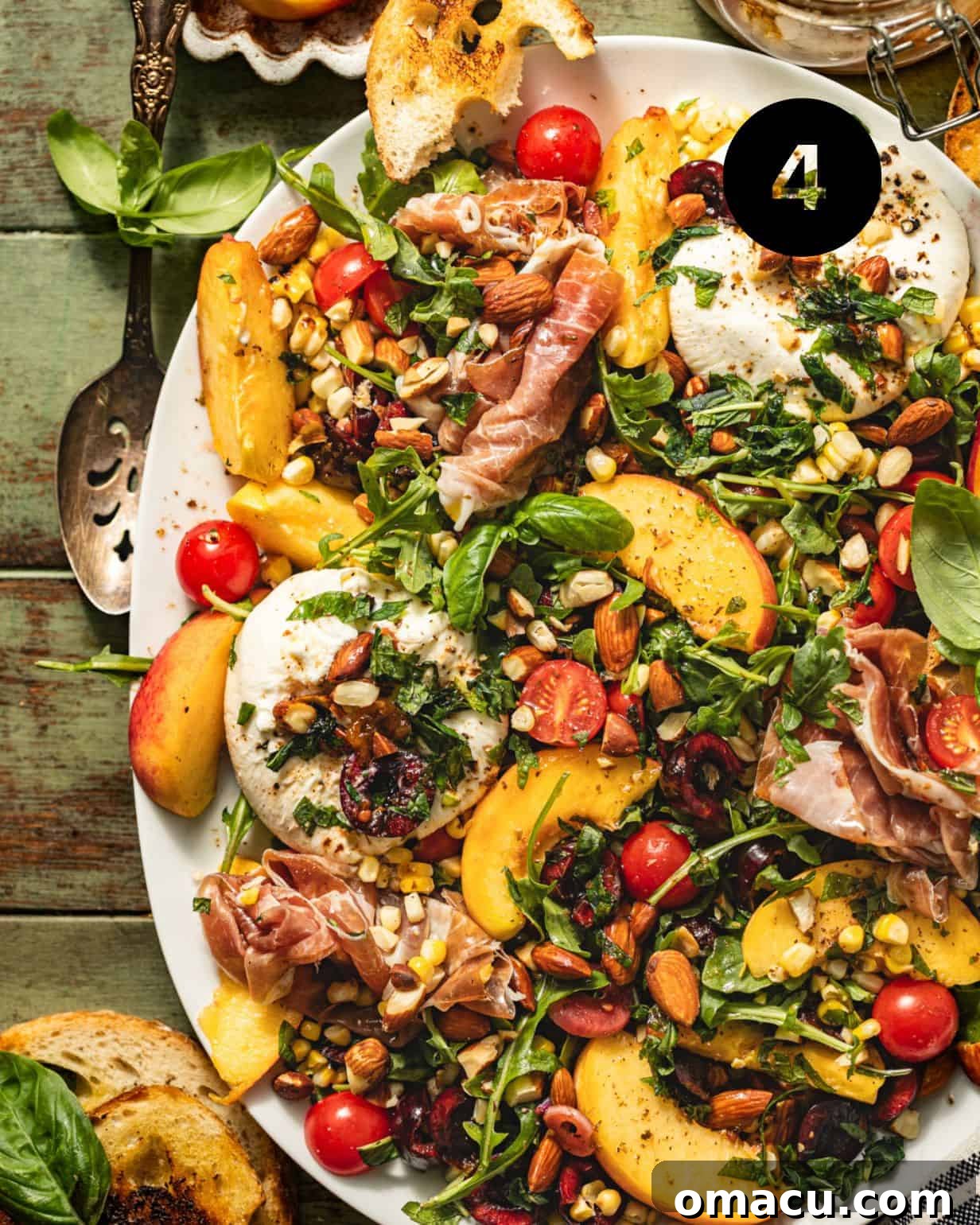 A beautifully assembled burrata salad on a serving plate, adorned with peaches, prosciutto, arugula, almonds, avocado, and cherries, ready to be served.