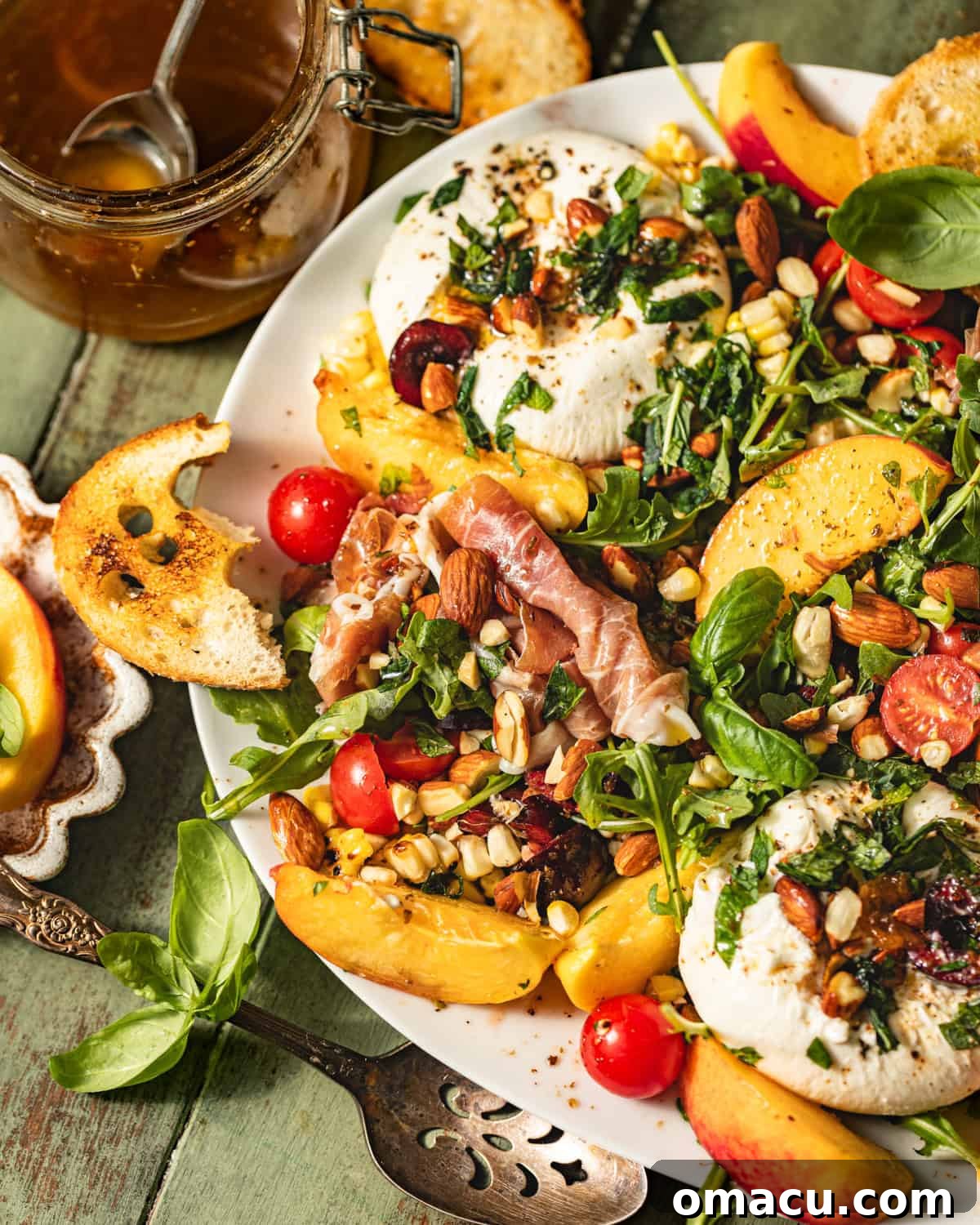 A close-up of a burrata arugula salad featuring fresh peaches, savory prosciutto, and vibrant mint, beautifully arranged on a serving plate.