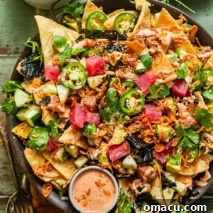 Poke Nachos on a serving dish topped with sliced jalapenos, garlic crisps, cucumbers, sesame seeds, and yum yum sauce.