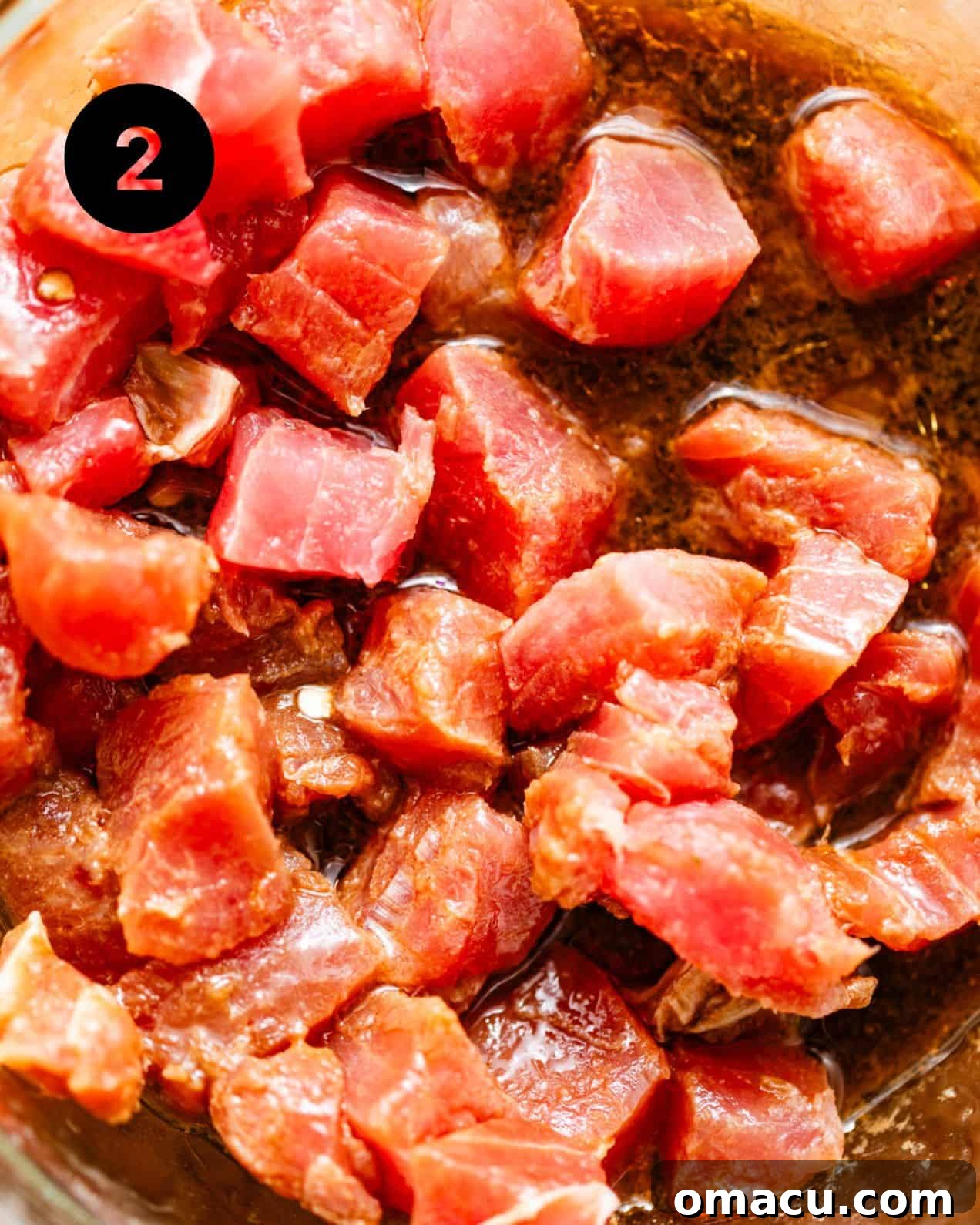 A bowl of marinated ahi tuna chunks, glistening with a flavorful poke nacho sauce, ready for assembly.