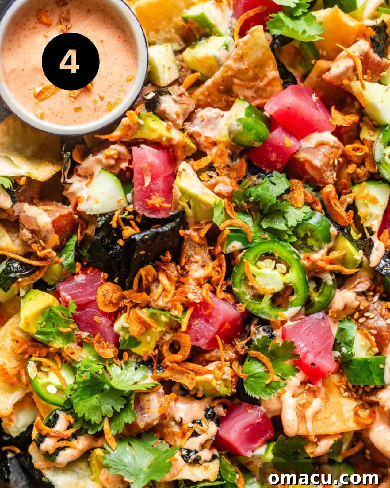 A beautifully assembled platter of poke nachos, laden with marinated tuna, vibrant toppings, and drizzled with sauce, ready for serving.