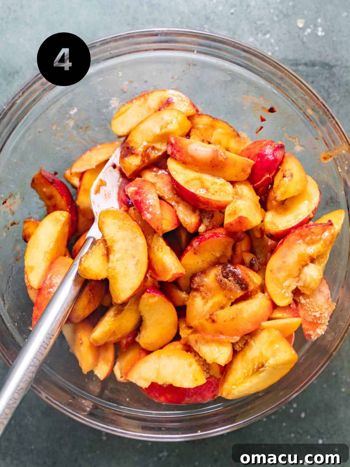 Fresh peach slices mixed with brown sugar, white sugar, lemon juice, spices, cornstarch, and melted butter in a large bowl.