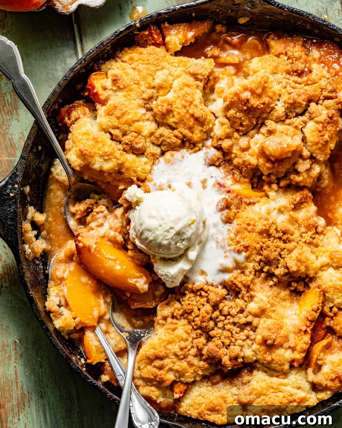 Freshly baked cast iron peach cobbler, bubbling hot, served with a scoop of vanilla ice cream.