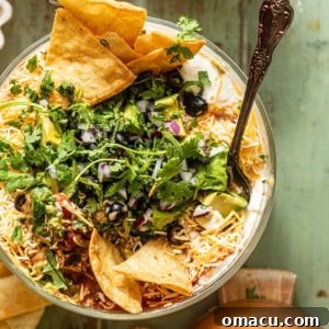 A top-down shot of the finished Five Layer Dip, garnished with fresh cilantro and a dollop of sour cream, ready to be served.