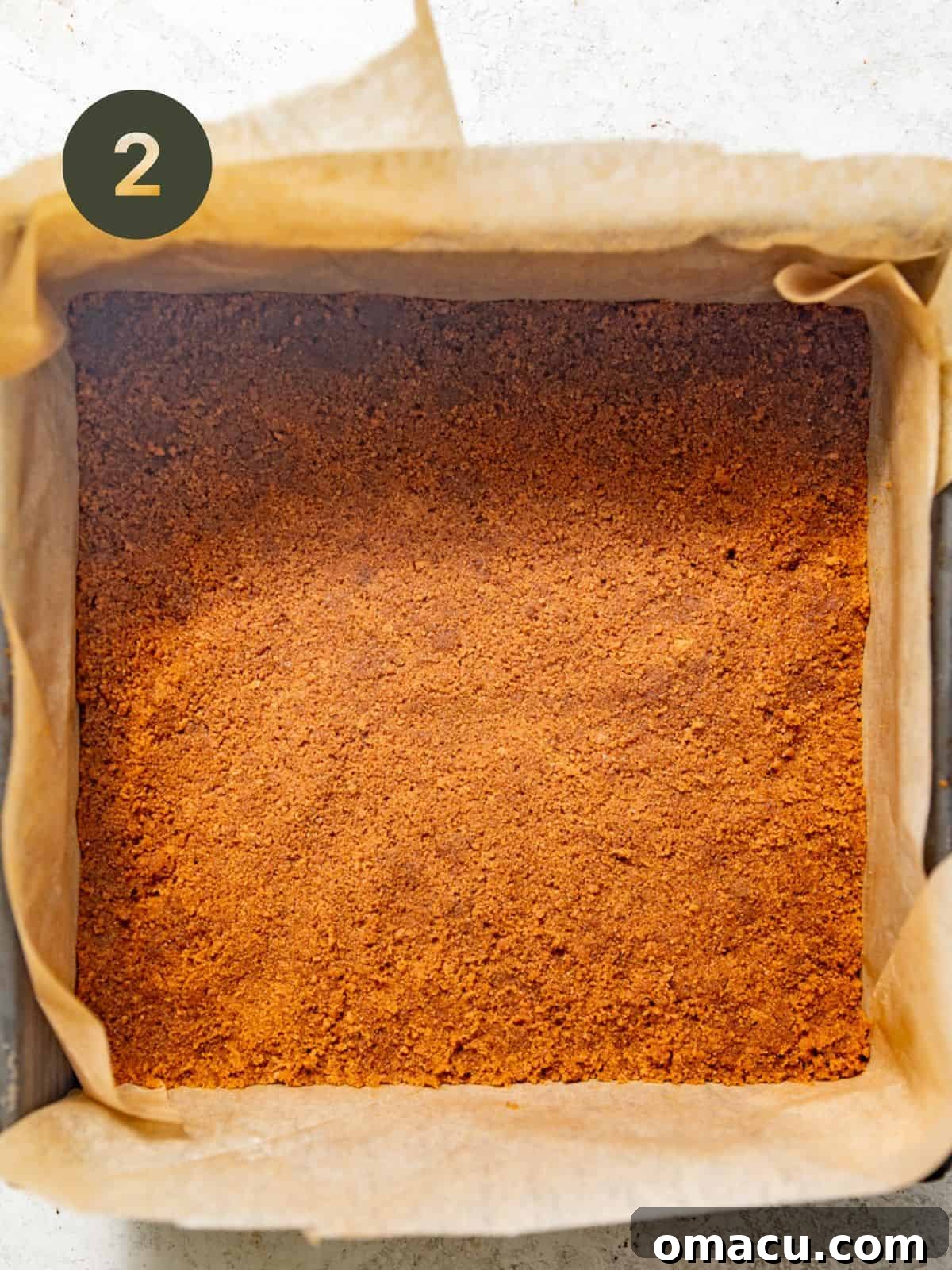 biscoff cookie crust in a baking pan lined with parchment paper.