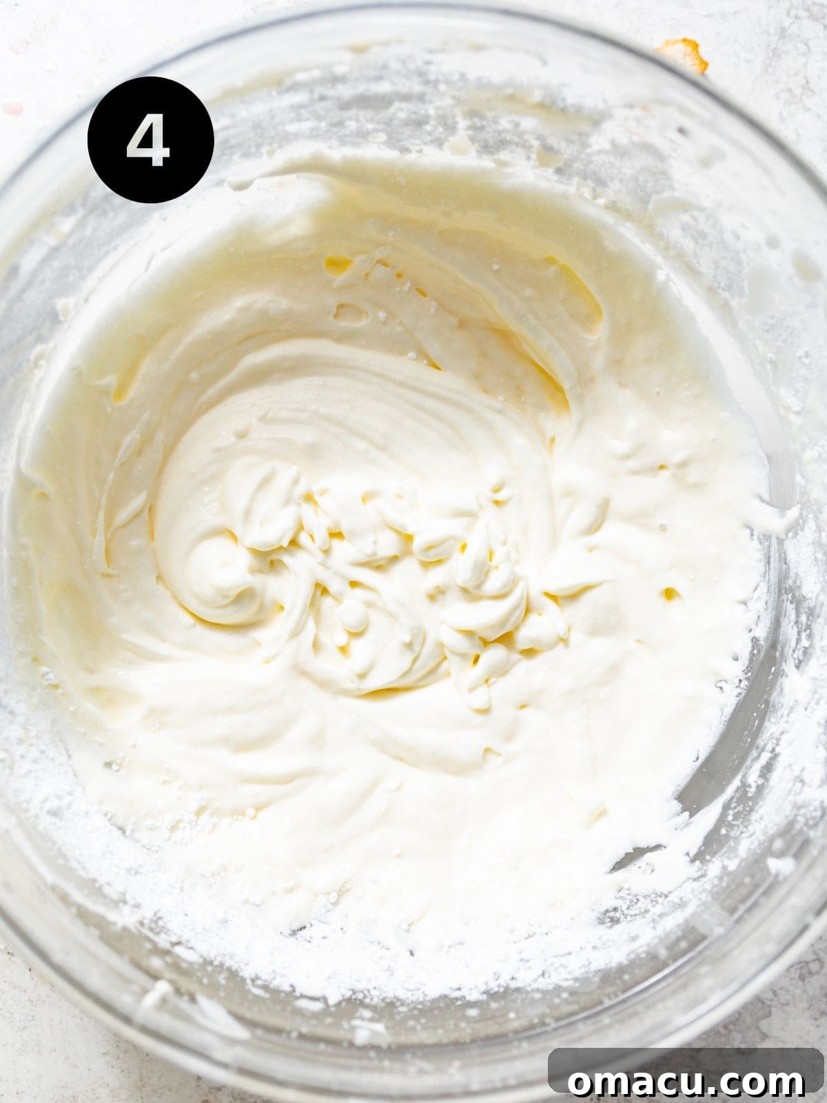 cream cheese, powdered sugar, and sour cream blended together in a bowl. 