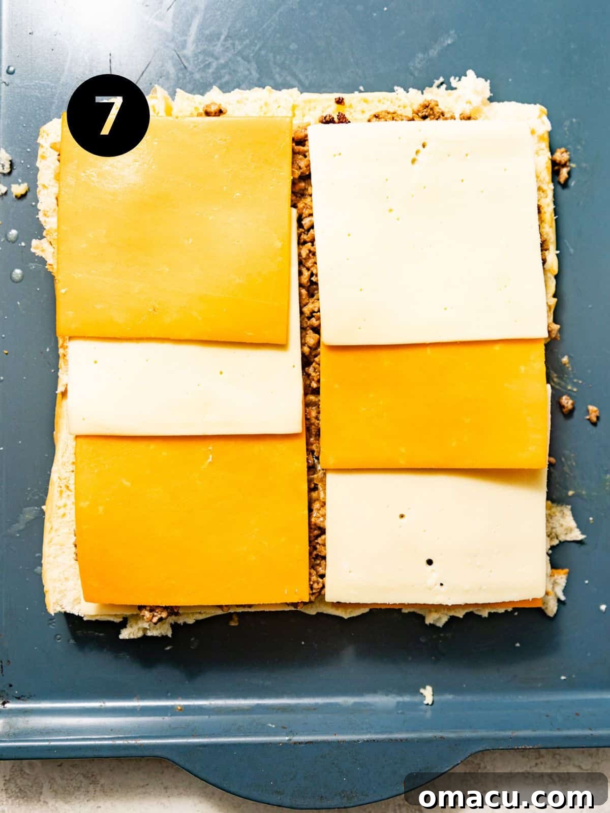The ground beef filling spread over the cheese layer on the Hawaiian rolls, topped with the remaining cheese slices.