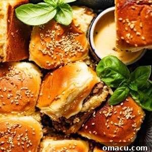 Cheeseburger sliders with Hawaiian rolls on a serving board with burger sauce and fresh basil.