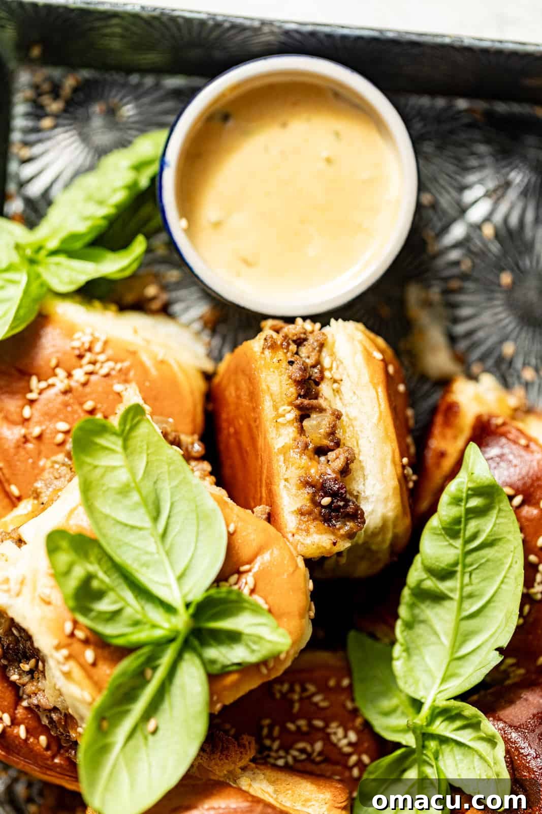 A single cheeseburger slider with burger sauce on a silver plate, ready to be enjoyed.