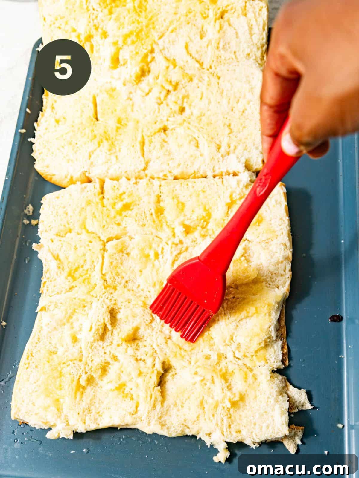 King's Hawaiian rolls sliced horizontally and brushed on the inside with garlic butter, arranged on a parchment-lined baking sheet.