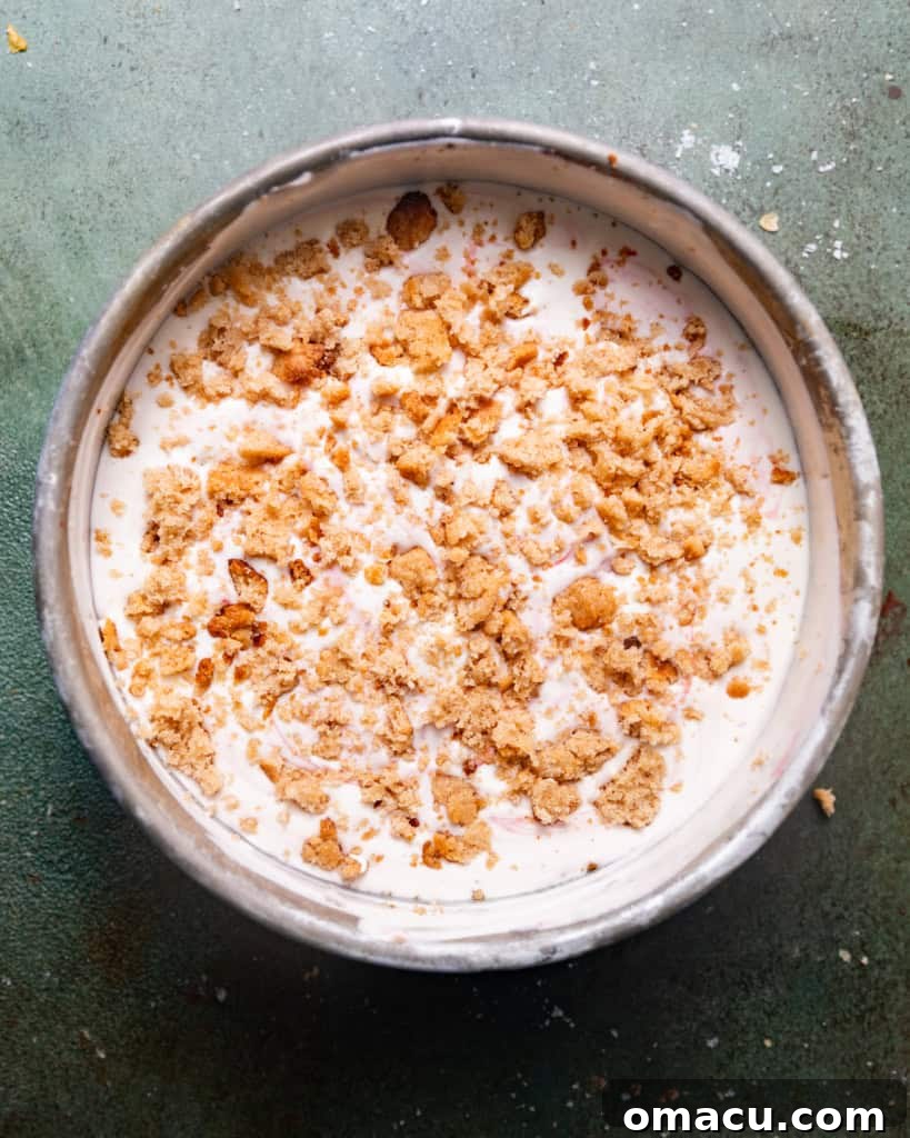 The finished strawberry shortcake ice cream, neatly arranged in a round pan, showing layers of ice cream and crumble, ready for freezing.