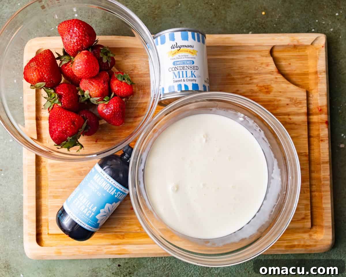 Main ice cream ingredients: fresh strawberries, a bottle of vanilla extract, a carton of heavy cream, and a can of sweetened condensed milk, artfully arranged on a wooden board.