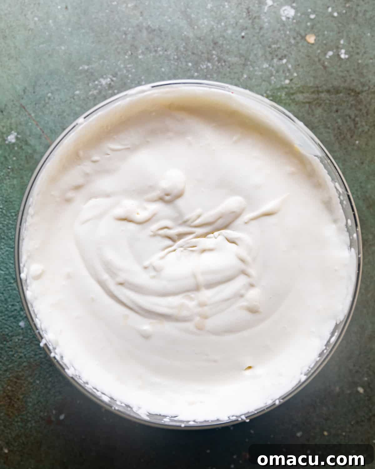 Heavy cream, perfectly whipped to stiff peaks, standing tall in a mixing bowl, ready to be folded into the ice cream base.