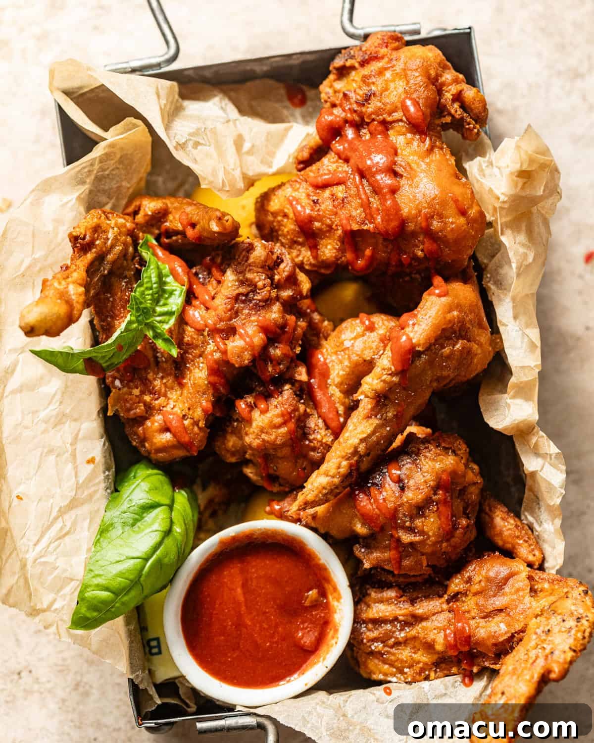 Crispy Chinese fried chicken wings served in a rustic basket, generously drizzled with a savory sauce, ready to be enjoyed.
