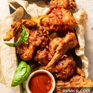 Chinese fried chicken in a basket with sauce drizzled on top.