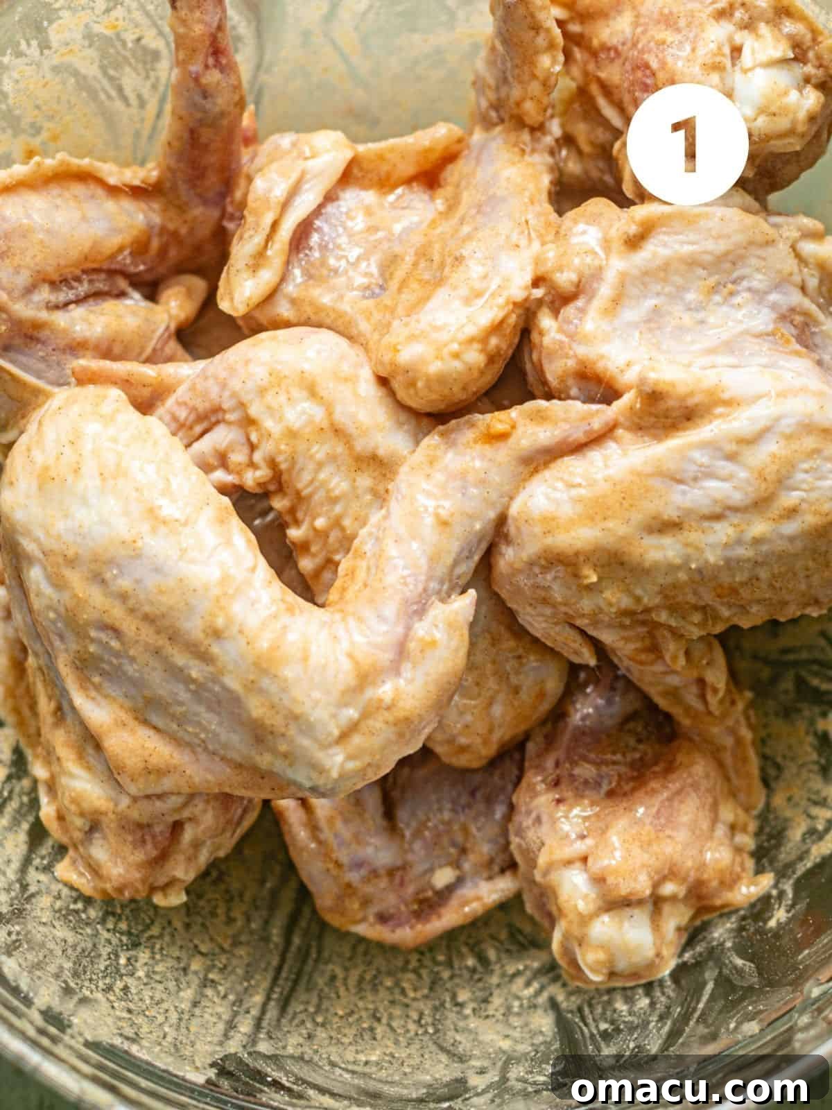 Chicken wings thoroughly covered in a rich, savory marinade in a mixing bowl, ready for the next step in the preparation process.