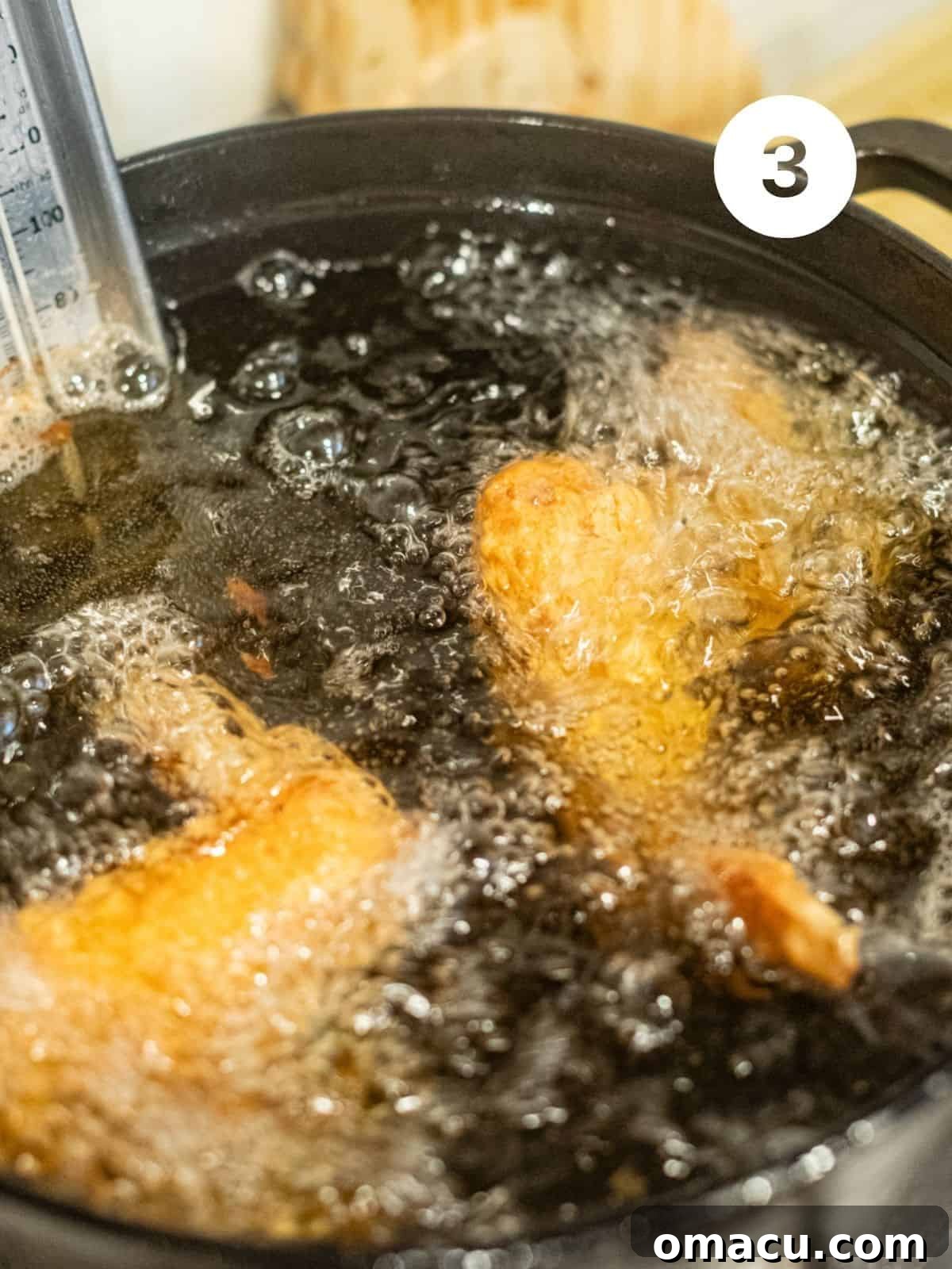Chicken wings actively frying in hot oil within a large pot, with a candy thermometer clipped to the side, ensuring precise temperature control for perfectly cooked wings.
