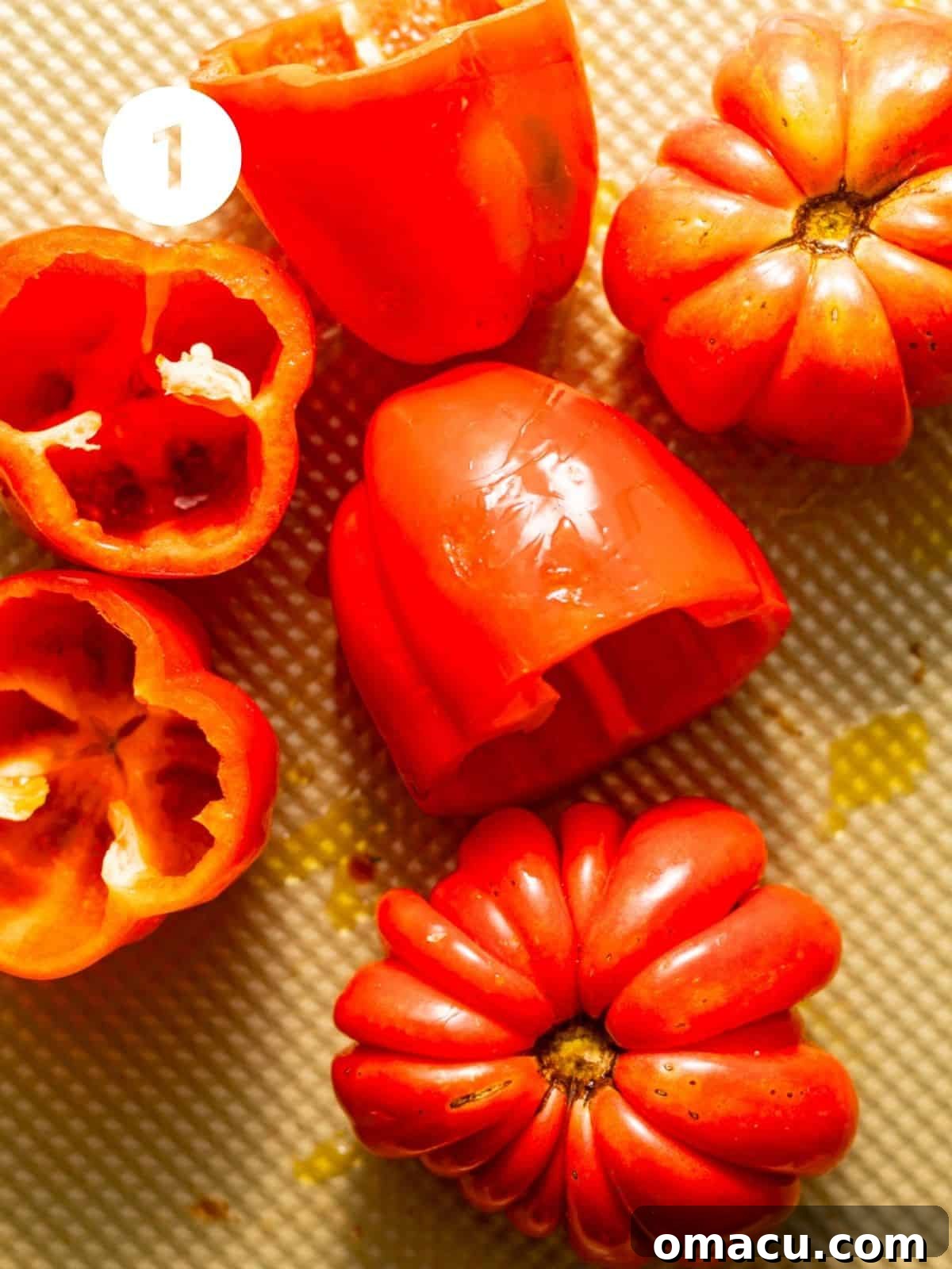 Whole red peppers and heirloom tomatoes perfectly arranged on a baking sheet, ready for roasting to bring out their rich flavors.