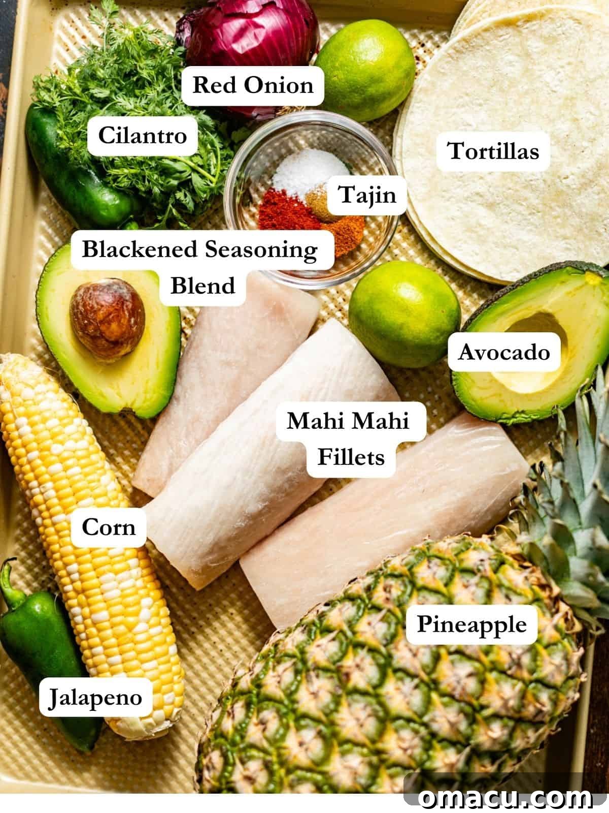 A beautifully arranged selection of fresh ingredients for preparing blackened mahi mahi tacos, including seasoned mahi mahi fillets, corn tortillas, vibrant pineapple chunks, sweet corn kernels, spicy jalapeños, creamy avocados, crisp red onion, zesty limes, Tajín seasoning, and aromatic cilantro, all neatly displayed on a baking sheet.