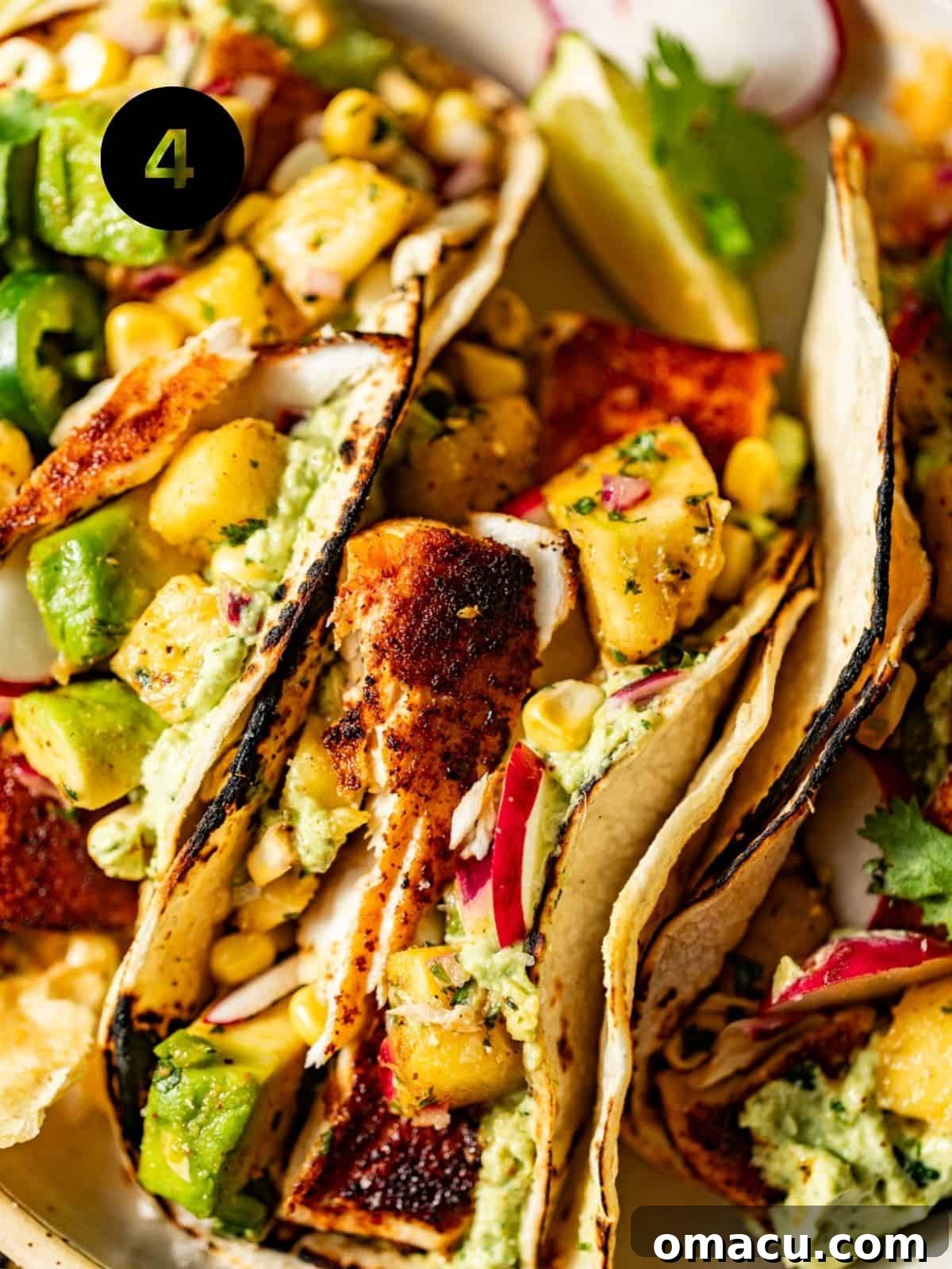 Beautifully assembled mahi mahi tacos on a white plate, generously adorned with fresh pineapple salsa, creamy avocado crema, and vibrant cilantro, ready to be enjoyed.