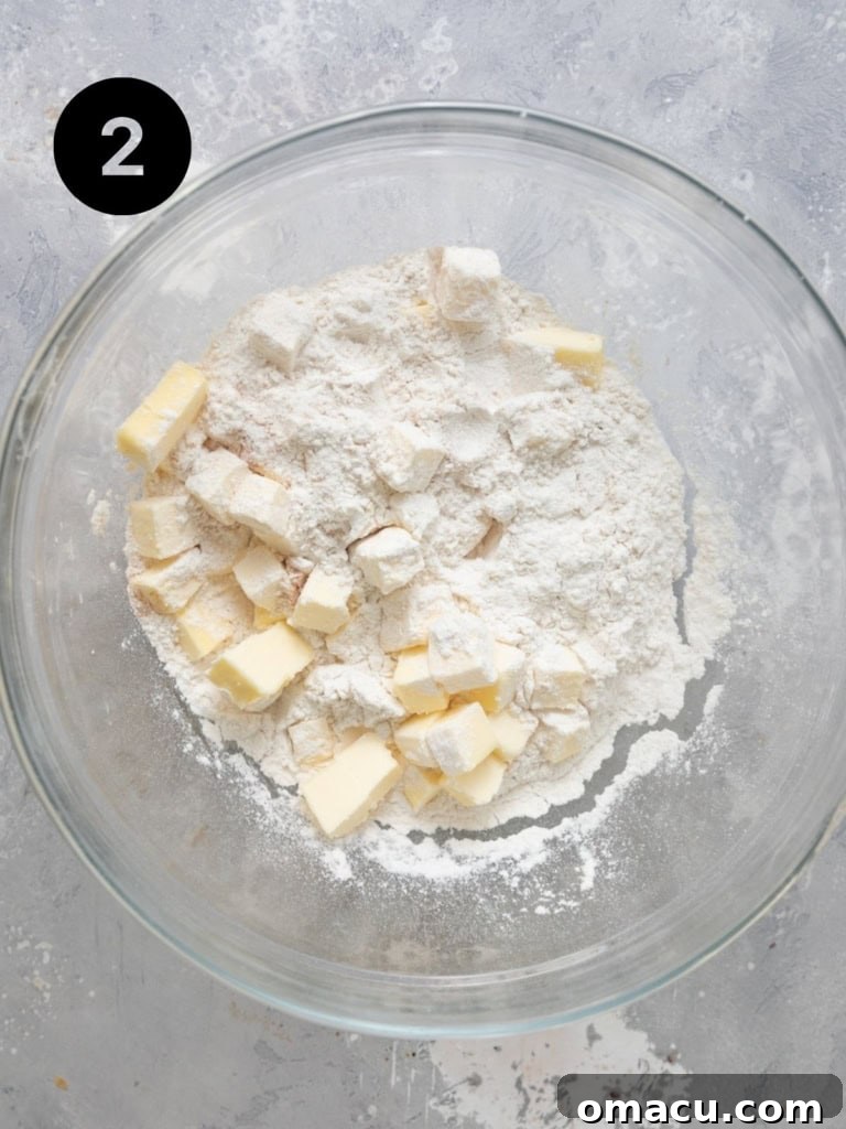 All-purpose flour and cold cubed butter in a mixing bowl, the initial stage of making the biscuit topping for cherry cobbler.