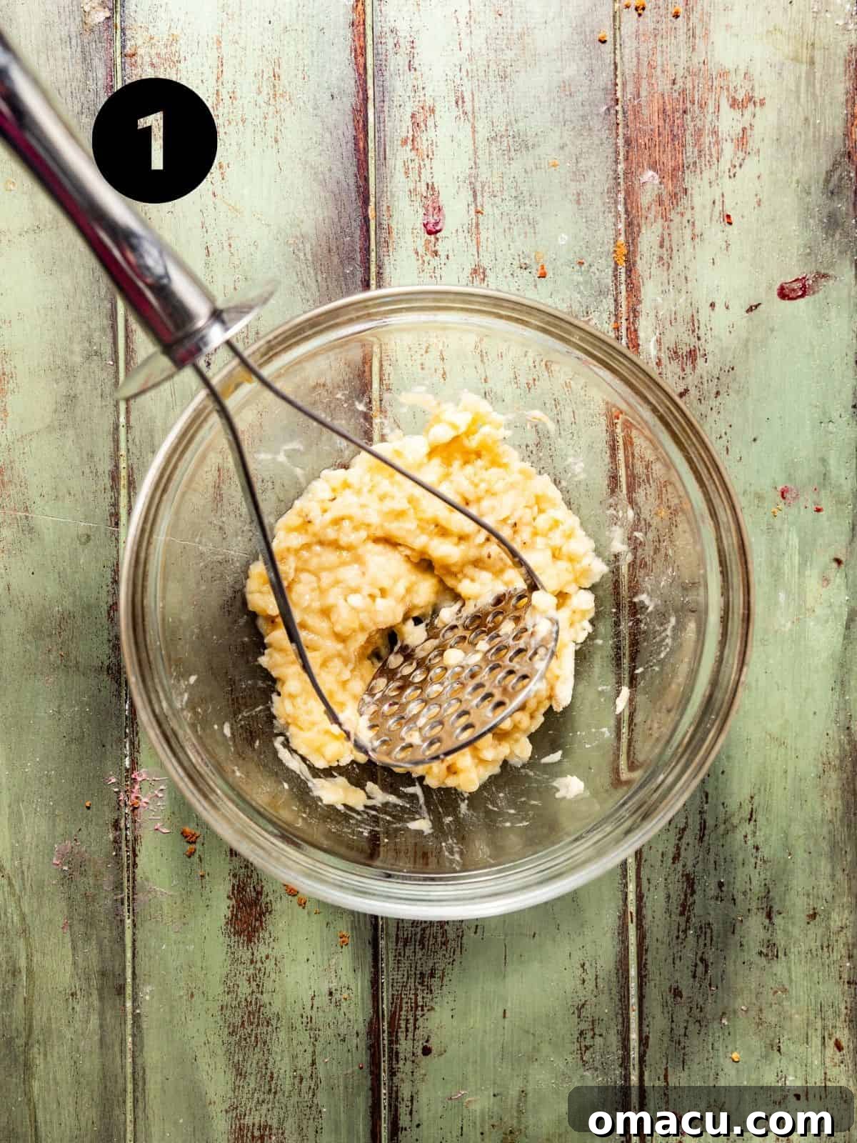 Mashed ripe bananas in a large mixing bowl, ready for the wet ingredients.