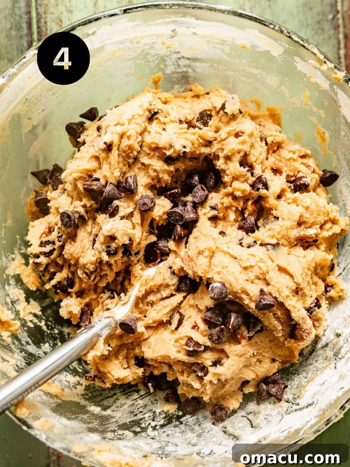 A bowl of freshly prepared banana chocolate chip cookie dough batter, with visible chocolate chips and pecans, ready for chilling.