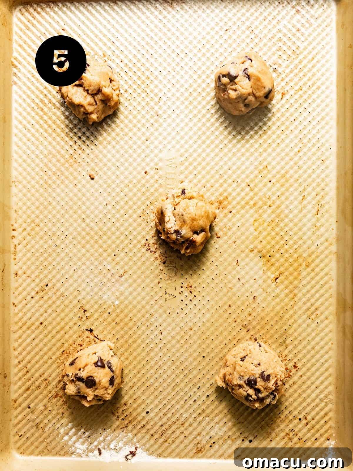 Scooped cookie dough balls, perfectly spaced on a parchment-lined baking sheet, ready for the oven.