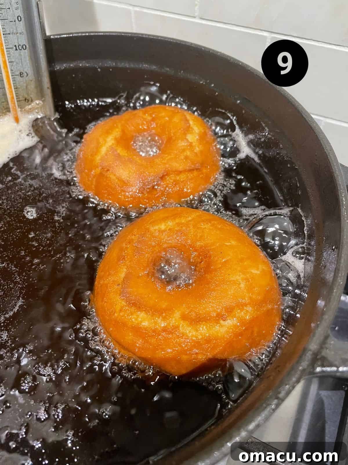 Pumpkin donuts being carefully placed into a pot of hot frying oil, showing the cooking stage.