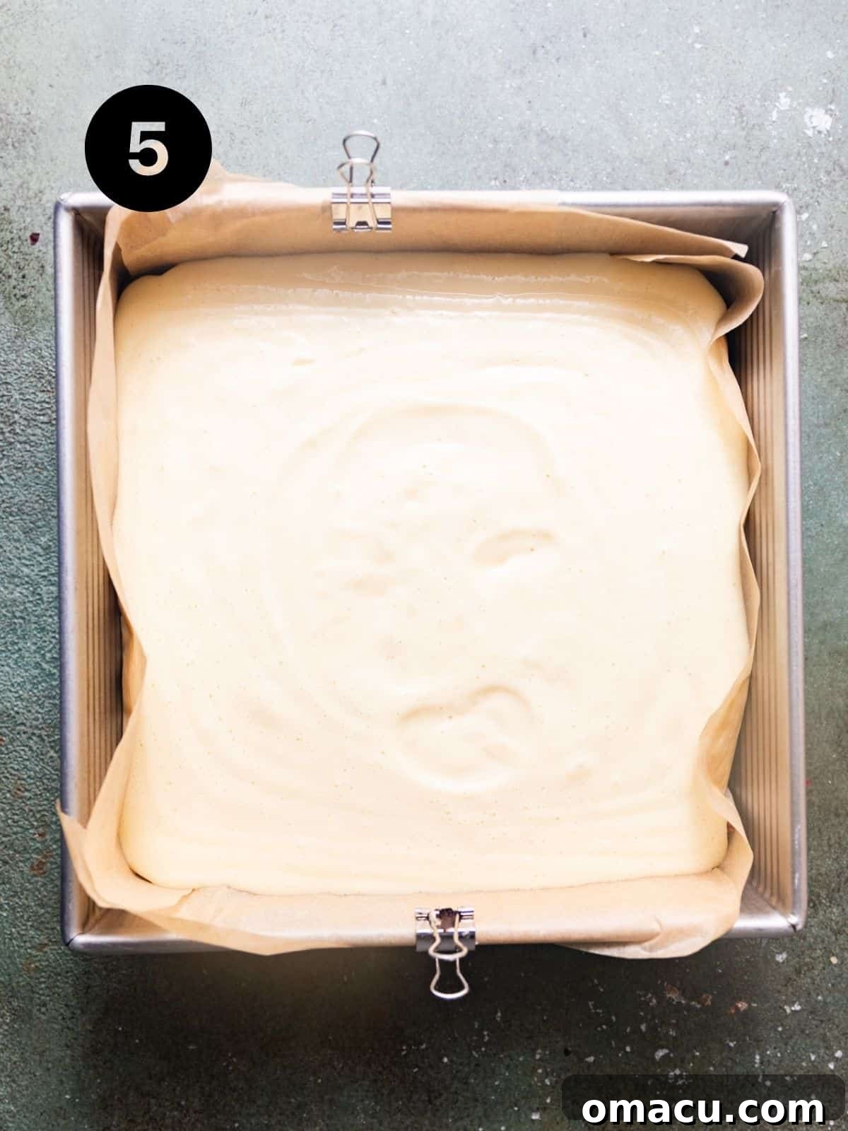 Key lime pie bars baking in a square pan, showing the vibrant green filling on top of the golden Biscoff crust, with edges just beginning to set.