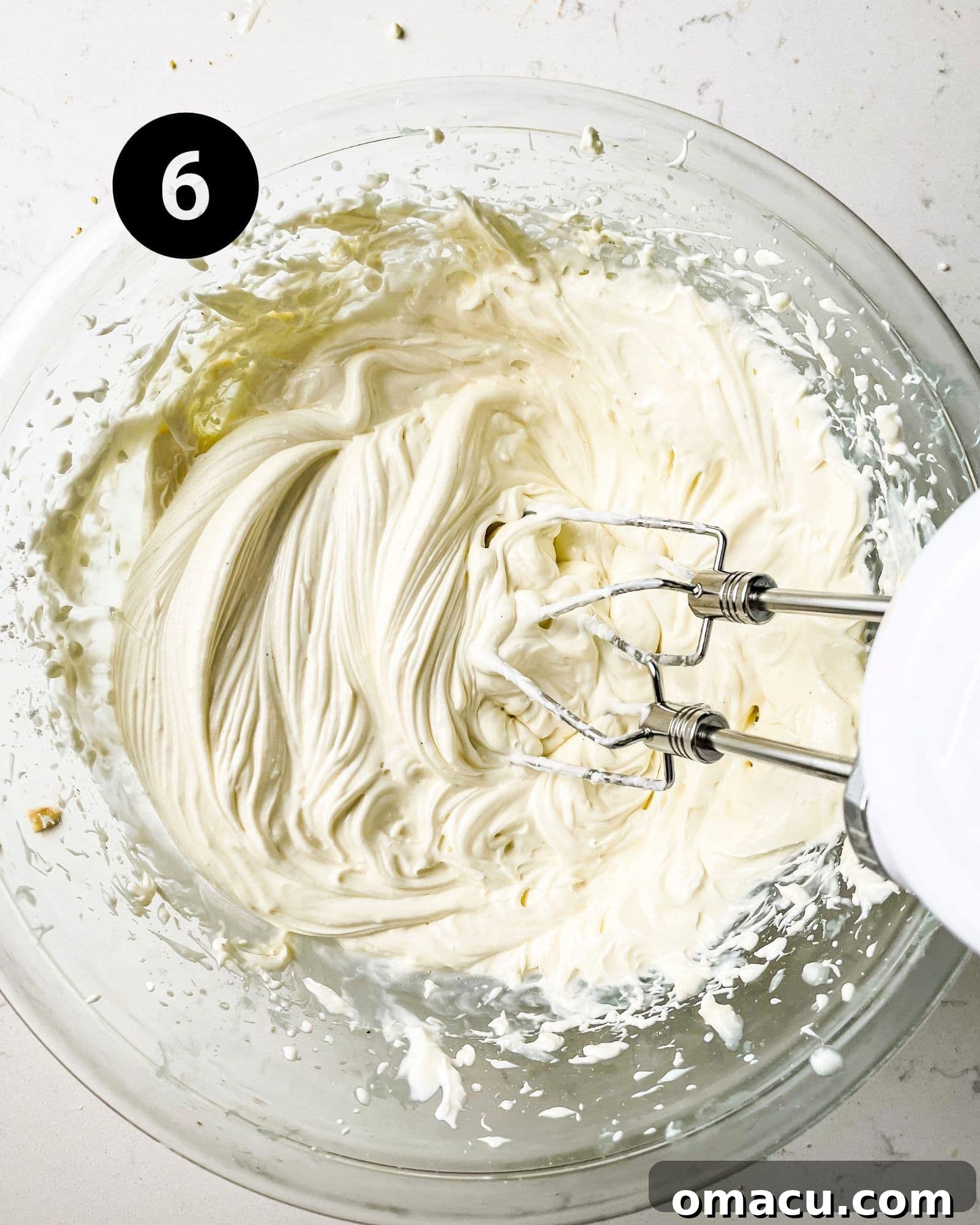 A large bowl filled with fluffy, stiff-peak whipped cream, indicating it's perfectly prepared for topping the key lime pie bars.